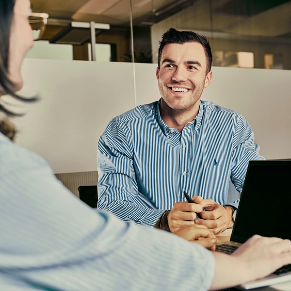 Zwei Personen aus dem Finance & Controlling Team sitzen an einem Schreibtisch und führen ein Gespräch. 