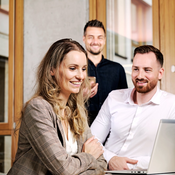 Eine Frau und zwei Männer aus dem Fleet & Remarketing Team unterhalten sich. Die Frau schaut dabei auf einen Laptop.
